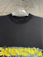 Black crewneck T-shirt with large yellow and blue paint-style graphic across chest