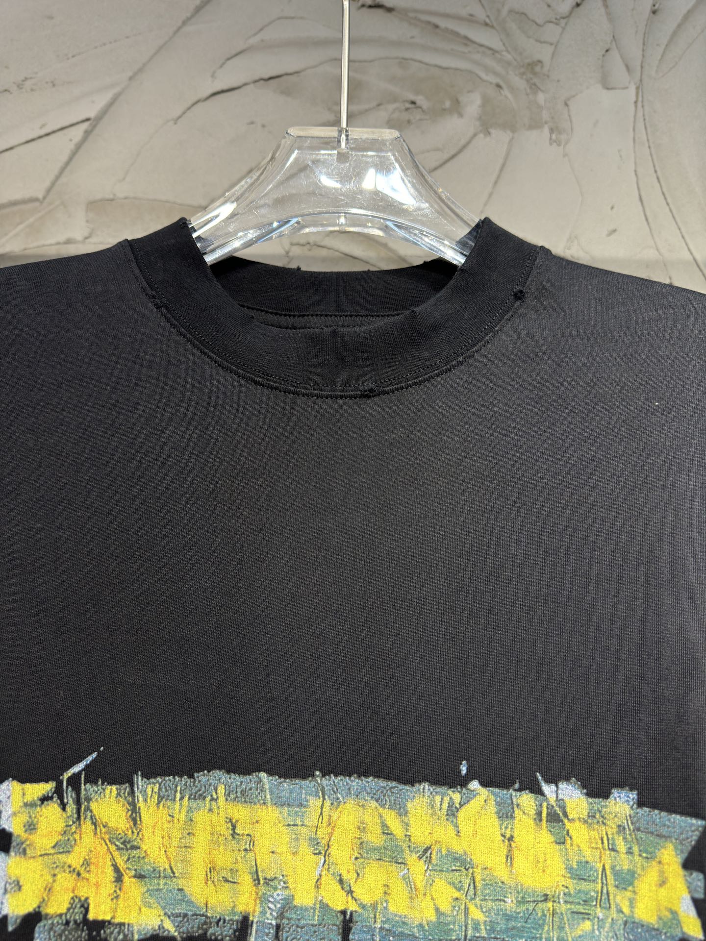 Black crewneck T-shirt with large yellow and blue paint-style graphic across chest