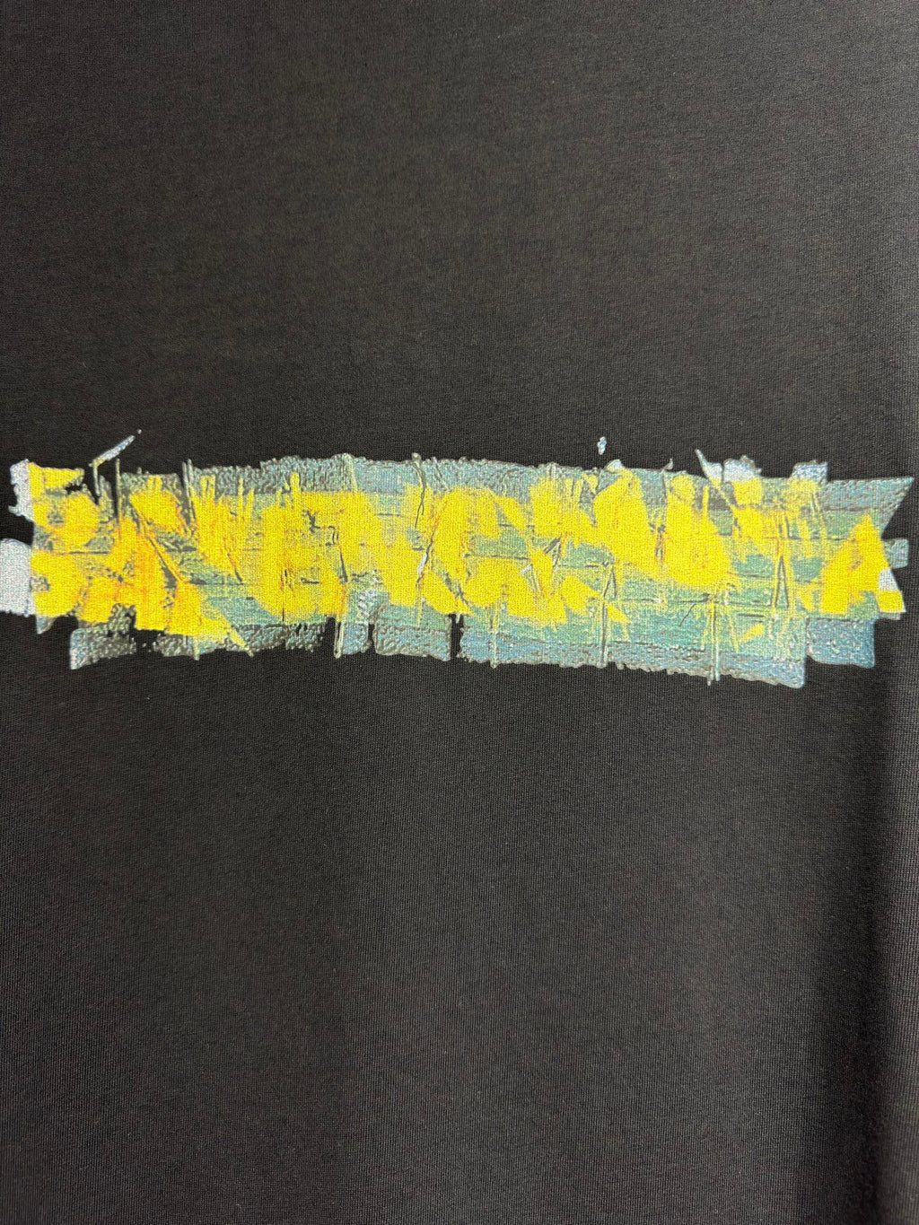 Black crewneck T-shirt with wide yellow and blue paint-style graphic across chest
