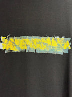 Black crewneck T-shirt with wide yellow and blue paint-style graphic across chest