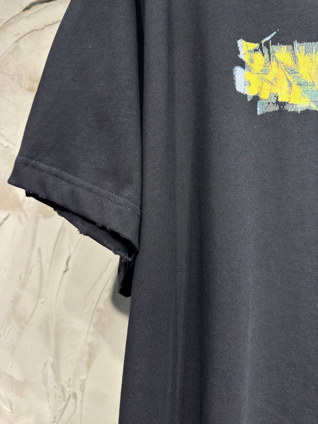 Black crewneck T-shirt with short sleeve cuff and yellow graphic on chest