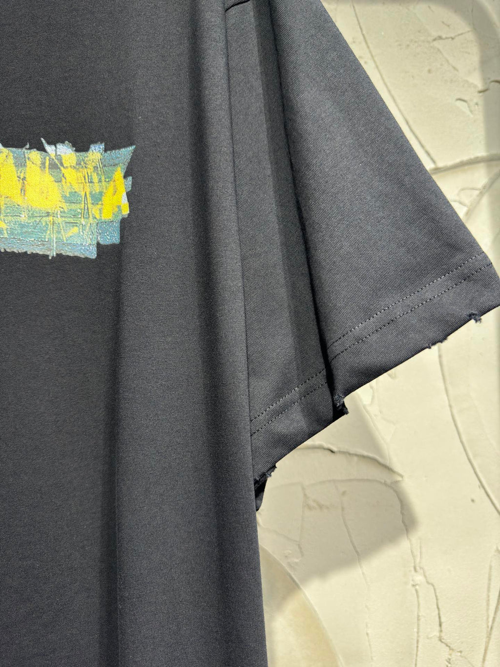Black crewneck T-shirt with visible short sleeve hem and partial yellow graphic