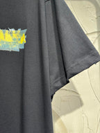 Black crewneck T-shirt with visible short sleeve hem and partial yellow graphic