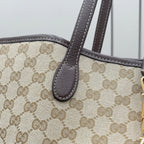 Gucci bag close-up with beige GG monogram canvas and brown leather handle