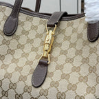 Gucci GG canvas tote bag close-up of gold zip pull and dark leather trim