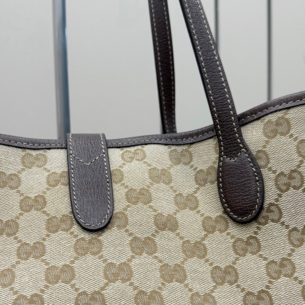 Gucci GG canvas tote bag close-up of dark leather handle tabs and stitching