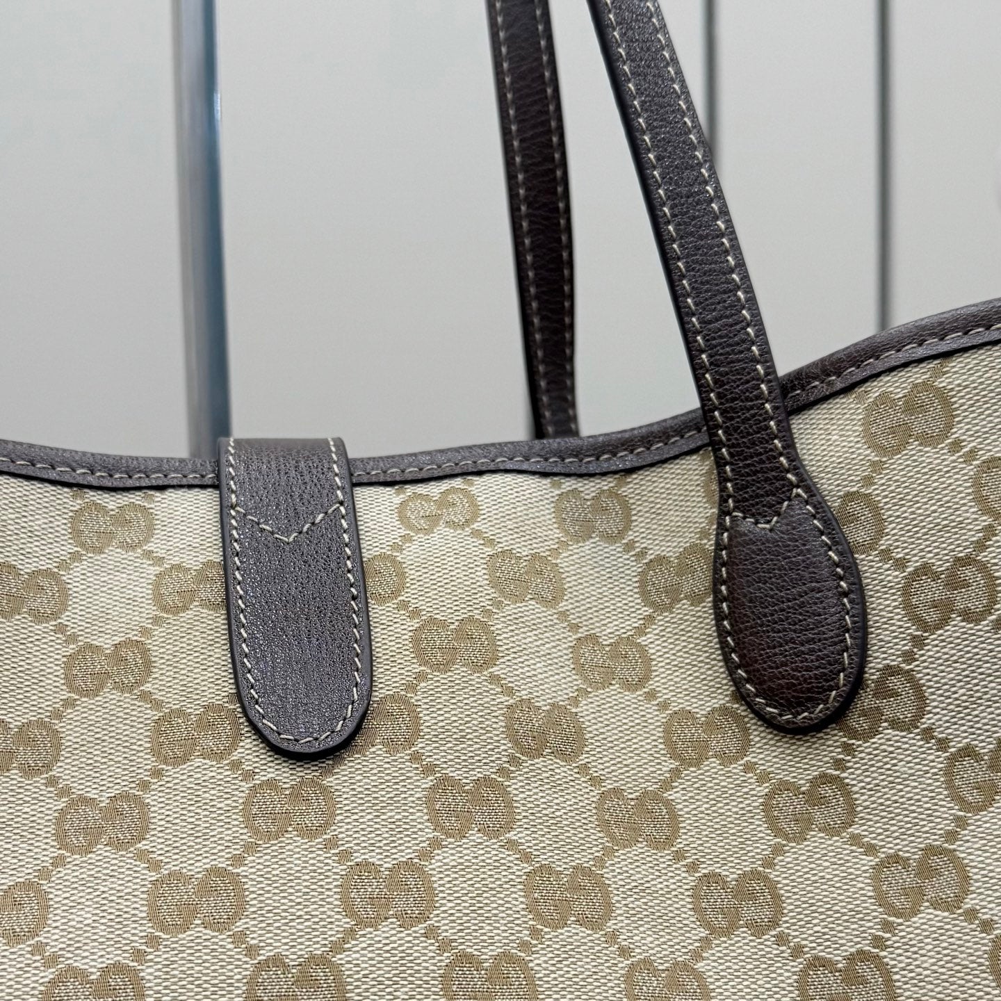 Gucci GG canvas tote bag close-up of dark leather handle tabs and stitching