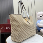 Gucci GG canvas tote bag with dark leather straps and gold clasp, side view