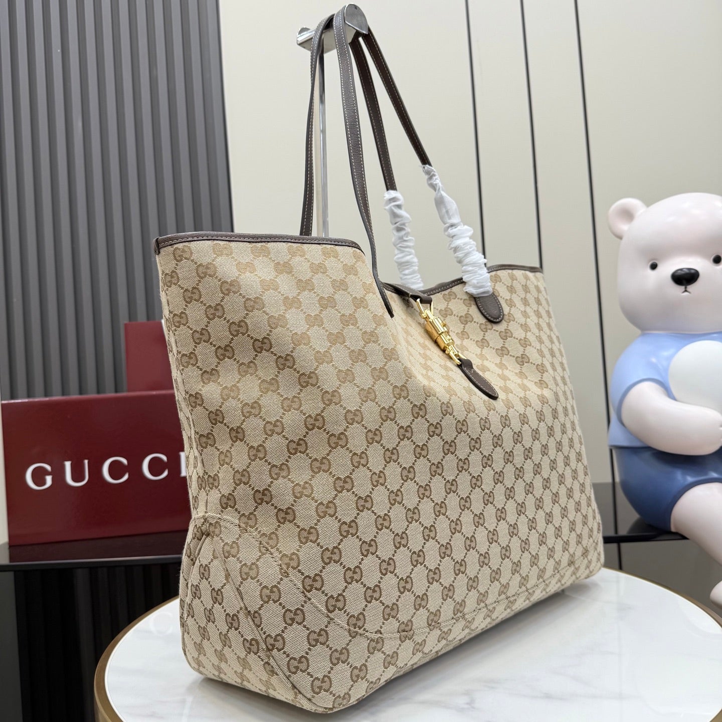 Gucci GG canvas tote bag with dark leather straps and gold clasp, side view