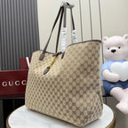 Gucci GG canvas tote bag with dark leather handles and gold hardware, angled view