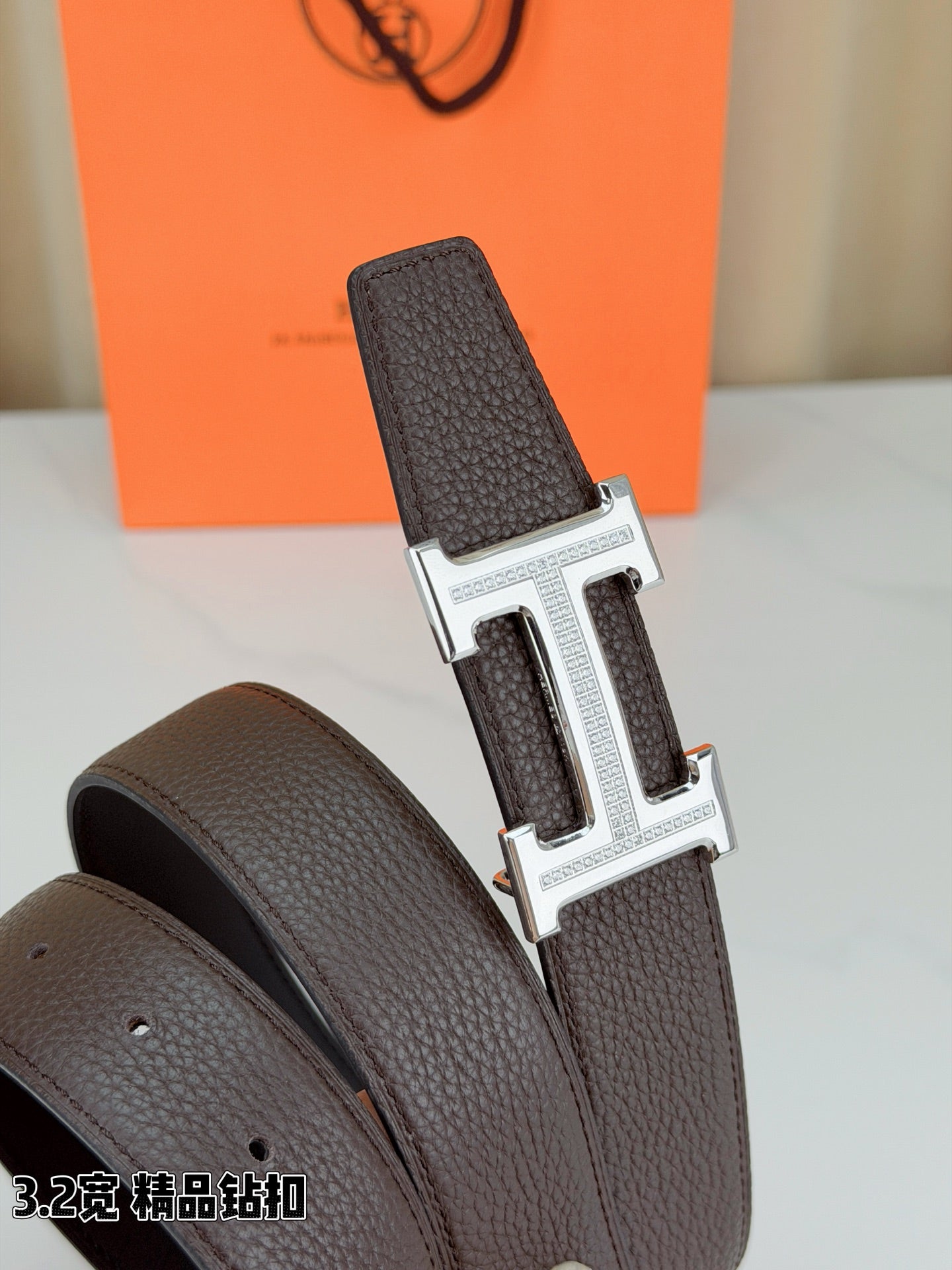 Dark brown leather belt with embossed texture and H buckle, side view