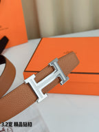Close-up leather belt with tan grained strap and silver H buckle