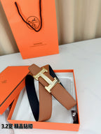 Leather belt with tan strap and silver H buckle, strap end and holes visible