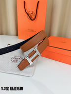 Tan and dark leather belt with silver H buckle, strap end and hole detail