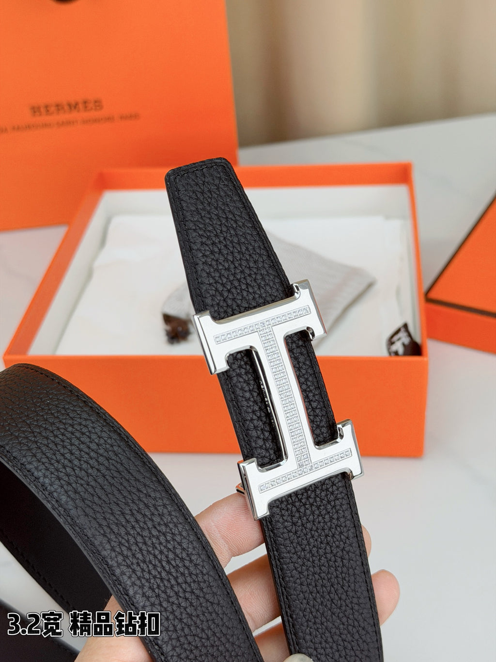 Hermes belt buckle detail: silver-tone H with dark pebbled leather strap