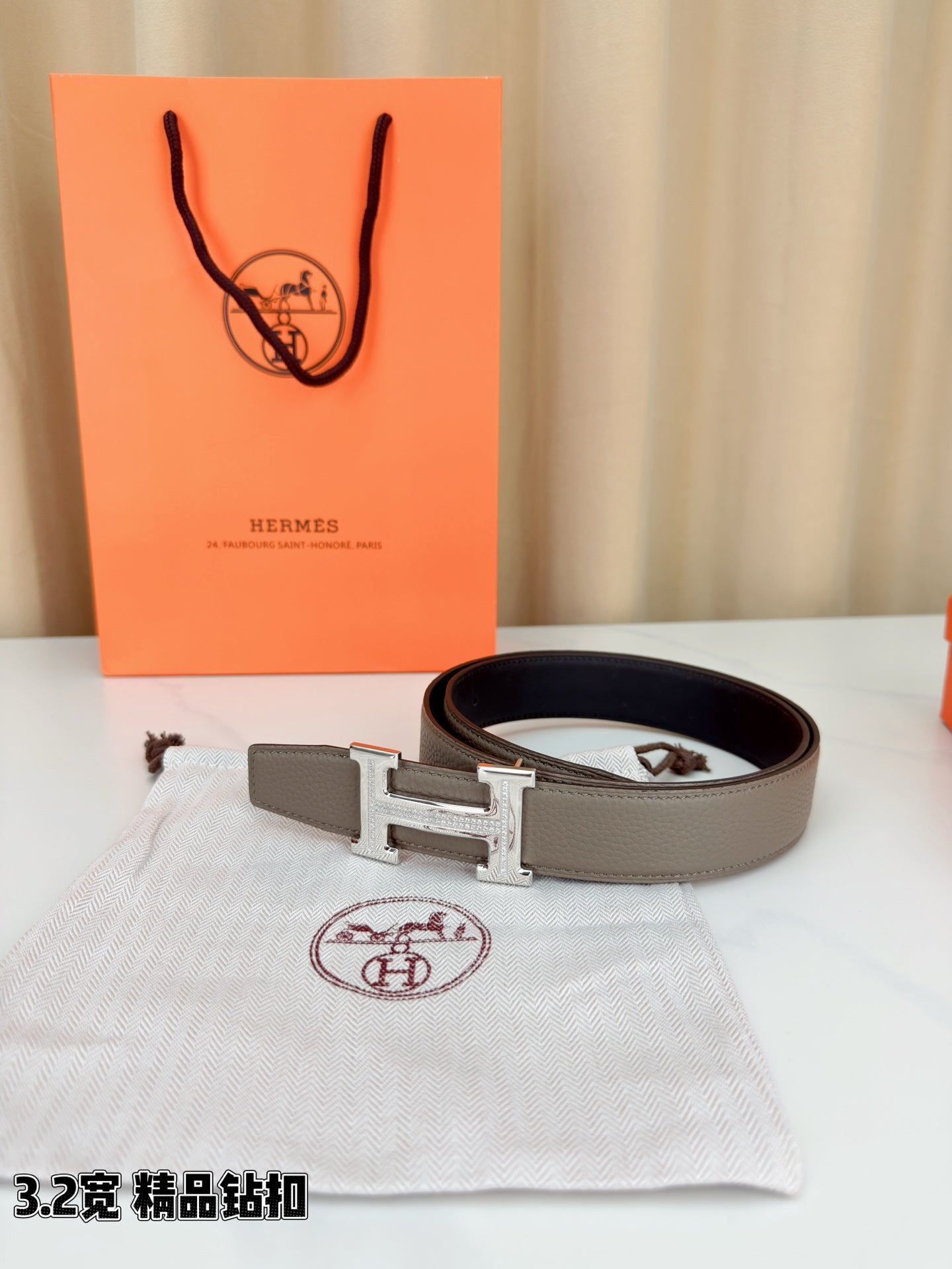 Light gray leather belt with gold-tone H buckle and dark belt tab detail