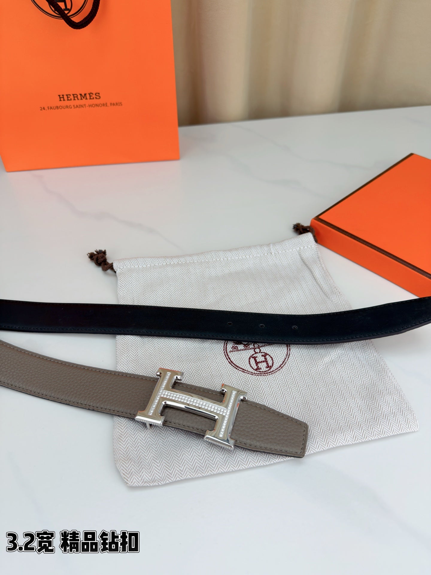 Light gray Hermes belt with silver-tone buckle, styled on white cloth