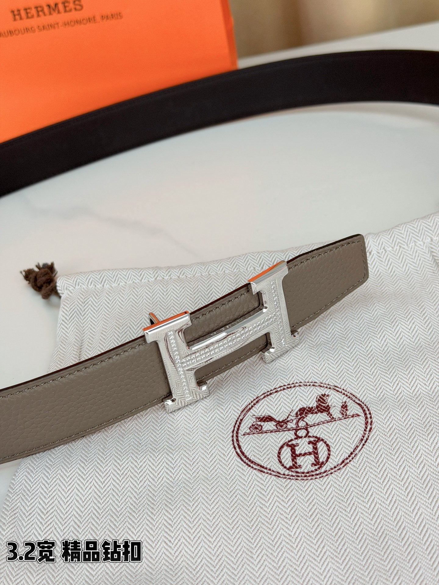 Light gray Hermes belt with silver-tone H buckle on patterned cloth