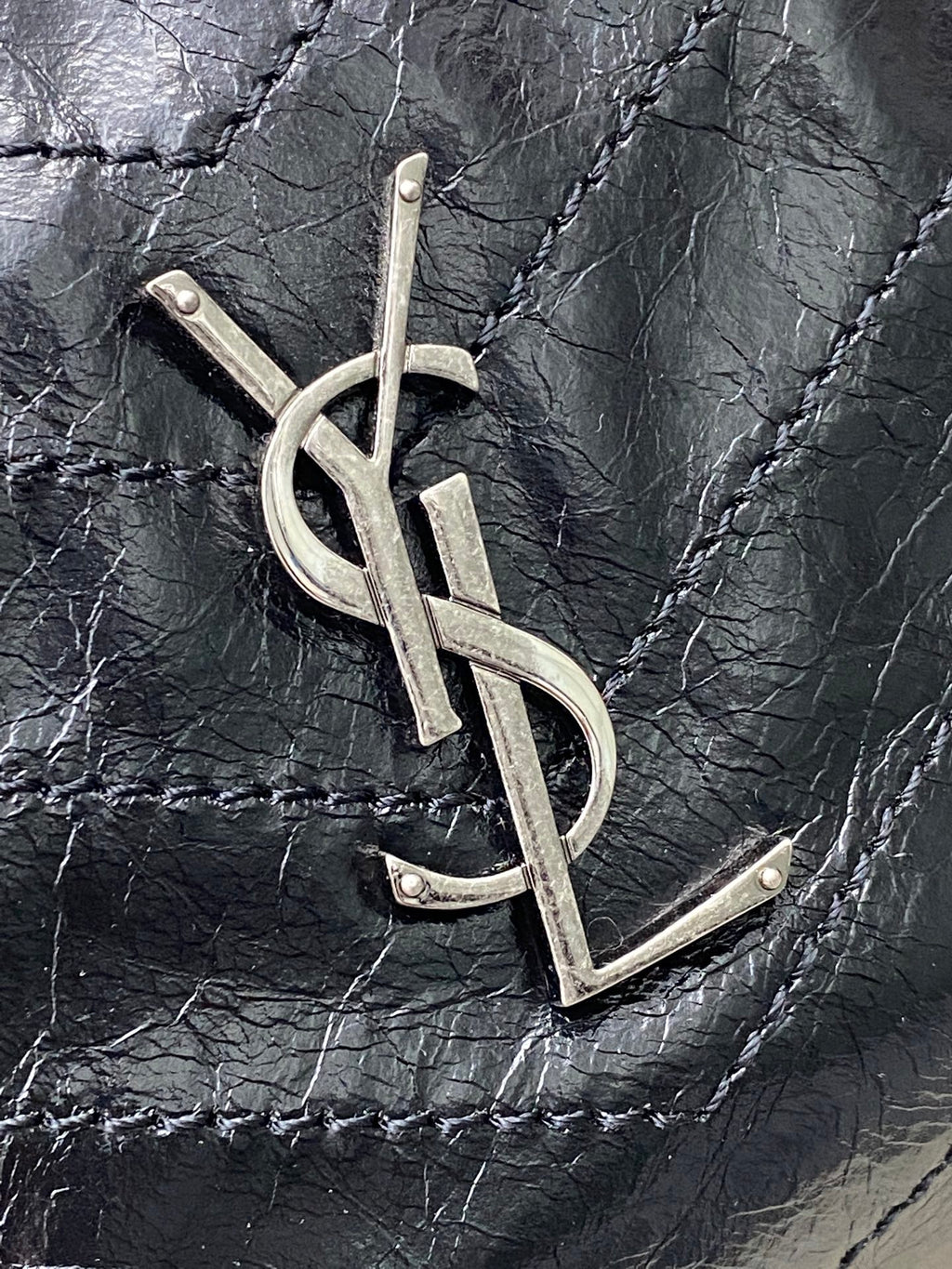 YSL metal logo on dark black quilted leather bag front