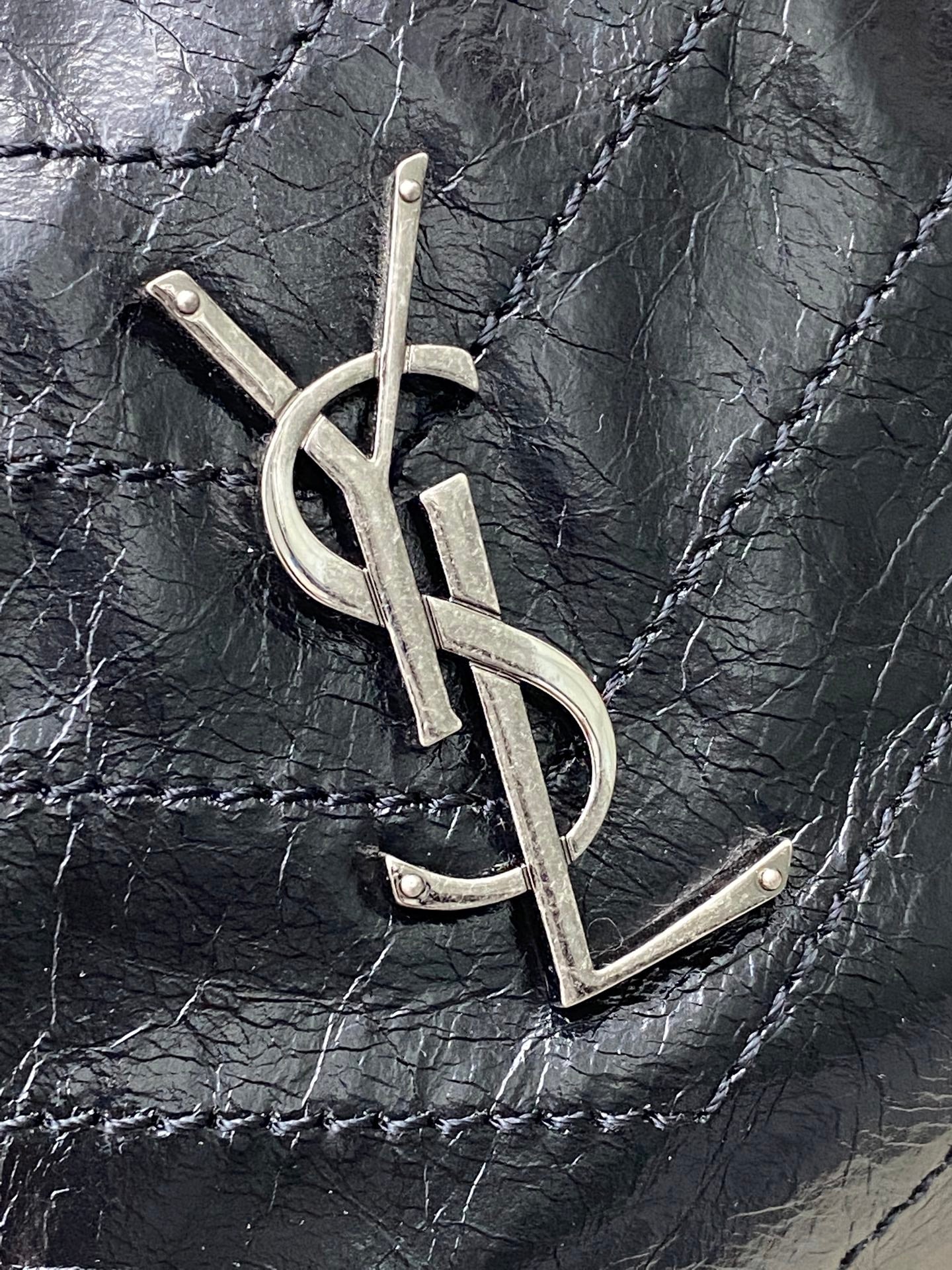 YSL metal logo on dark black quilted leather bag front
