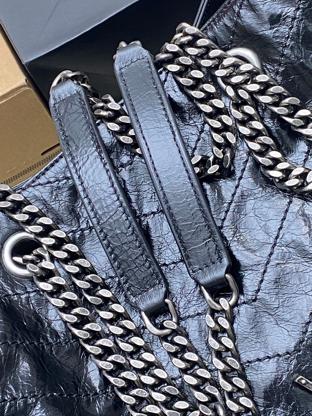 Dark black bag with silver chain strap and studded hardware details on strap