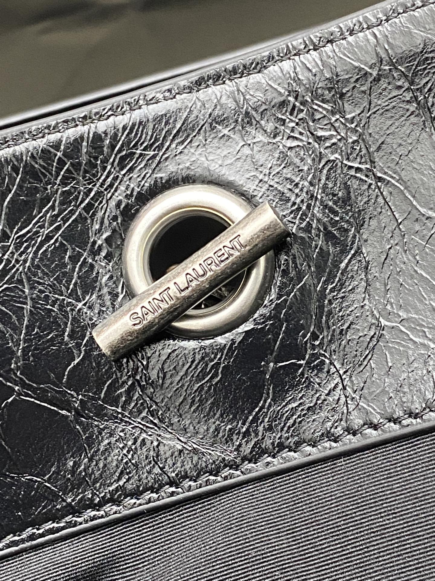 Black leather bag O-ring hardware with Saint Laurent fabric tag