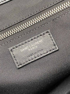 Logo patch on black leather bag near zipper with metallic teeth trim