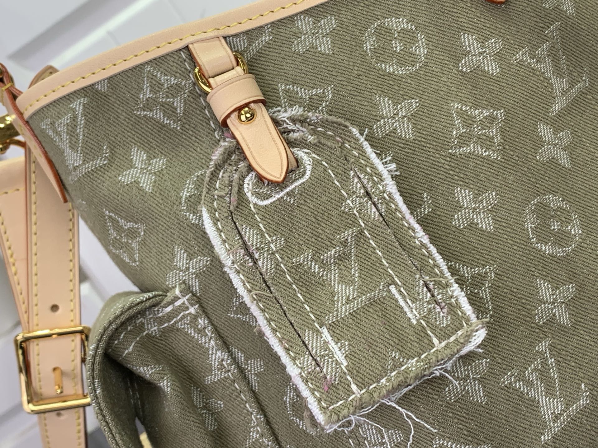 Olive monogram bag close-up with stitched leather strap and woven edging