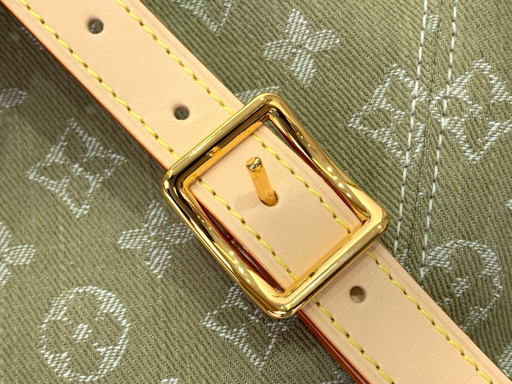Gold-tone buckle on tan leather strap with eyelets and stitched detail