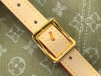 Gold-tone buckle on tan leather strap with eyelets and stitched detail