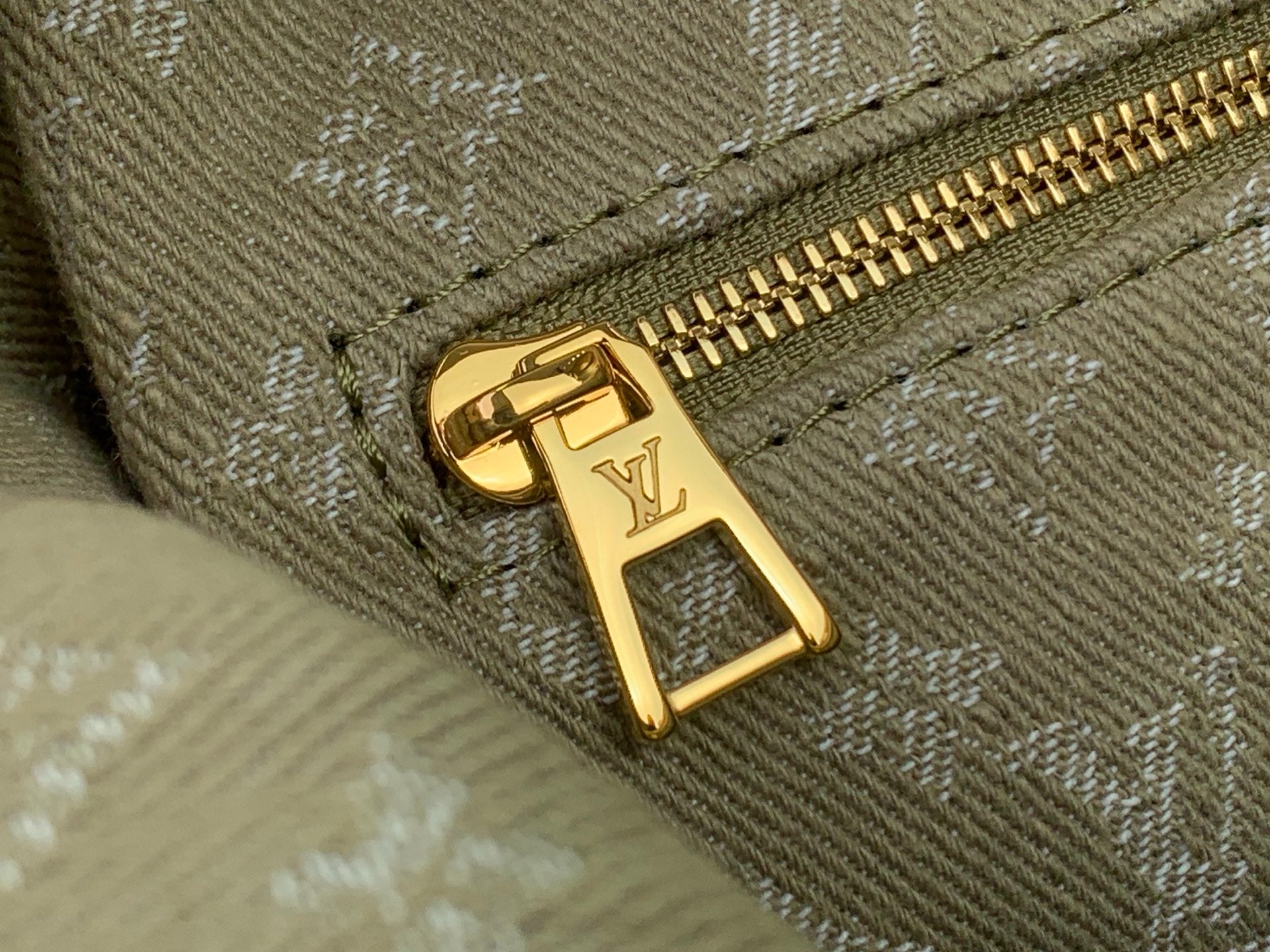 Gold LV monogram zipper pull on olive canvas bag