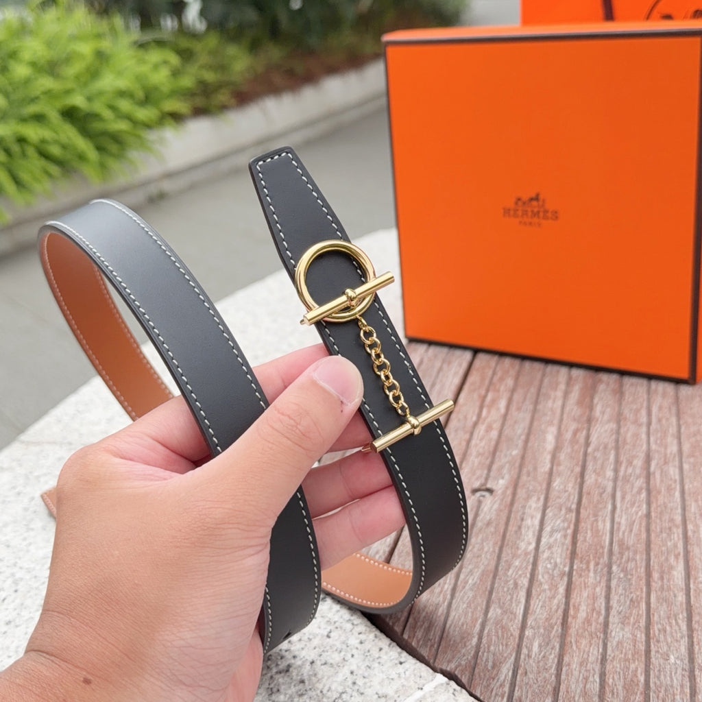Hermes belt shown by hand, dark navy strap with gold buckle and tan lining
