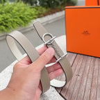 Belt showing adjustable holes, light gray-beige leather with silver buckle hardware
