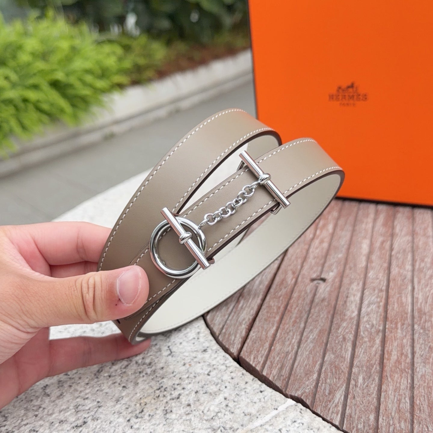 Belt with light gray-beige strap, round silver ring buckle and chain accent