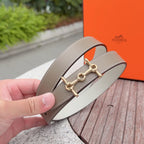 Taupe leather belt with gold-tone buckle, close-up in hand