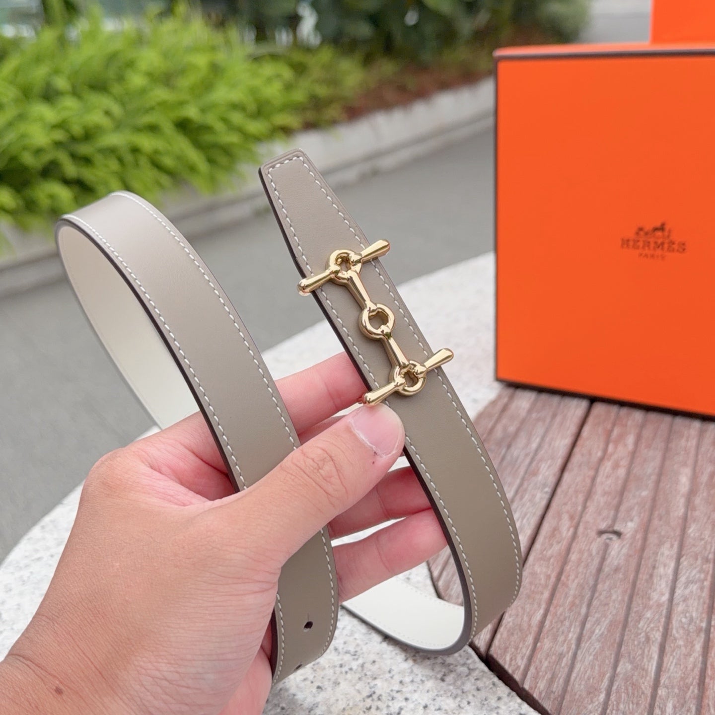 Taupe leather belt with gold-tone buckle, angled close-up