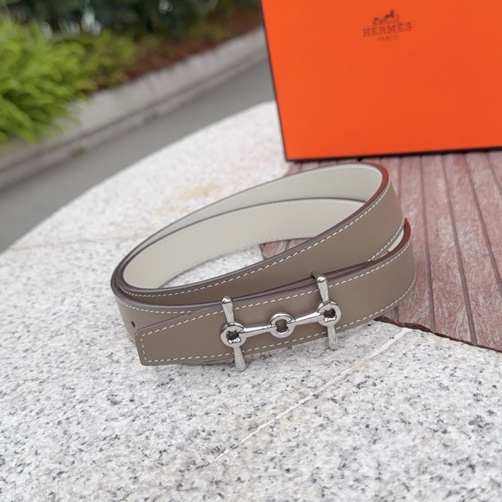 Hermes belt with light tan leather strap and silver buckle detail, shown in profile