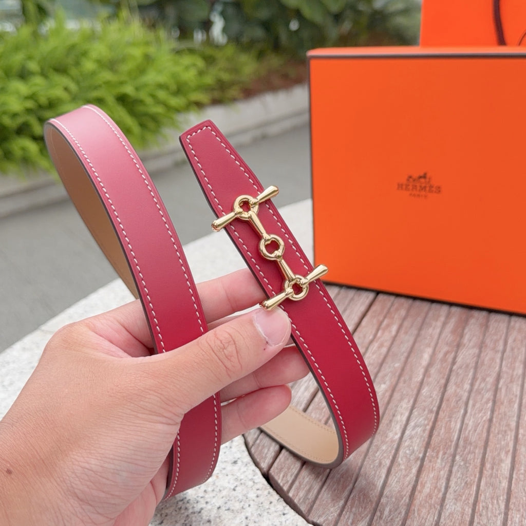 Hermes leather belt on hand, red strap with stitched edges and gold-tone clasp.