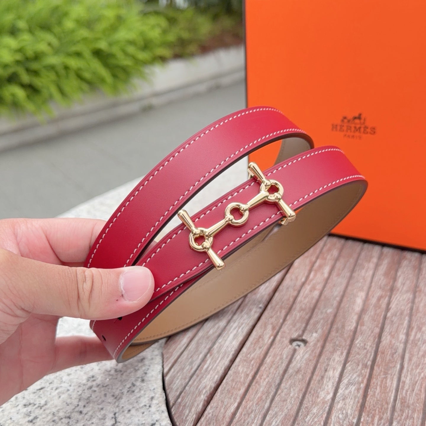 Hermes leather belt close-up, red leather strap with gold-tone buckle and tan lining.