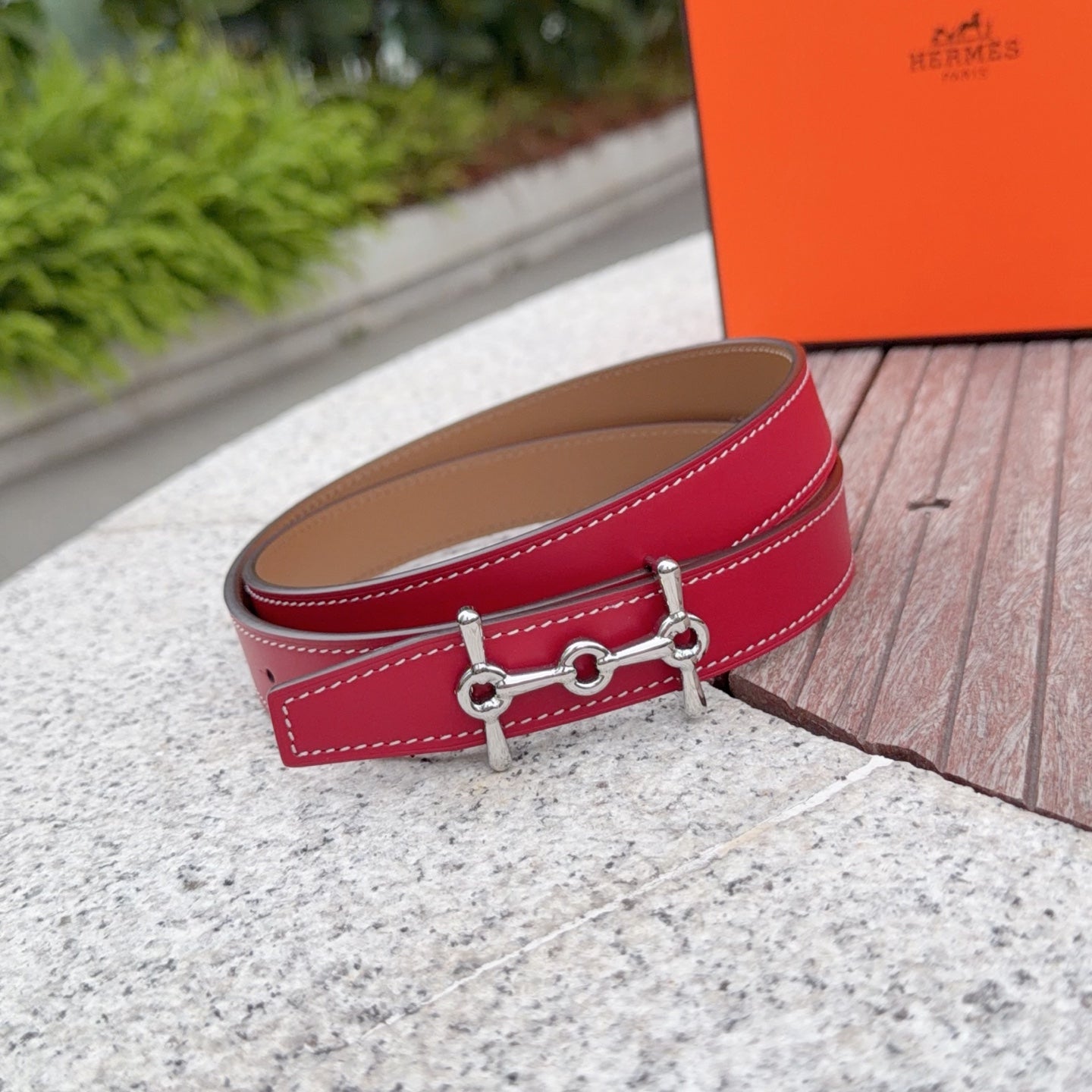 Red leather belt with tan lining, silver buckle hardware and stitched edge