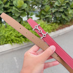 Red leather belt with tan adjustment holes on underside, silver buckle centerpiece