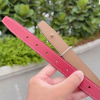 Red leather belt with tan reversible strap and punched adjustment holes, close-up