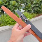 Hermes belt, dark leather with orange-brown underside and silver buckle hardware.