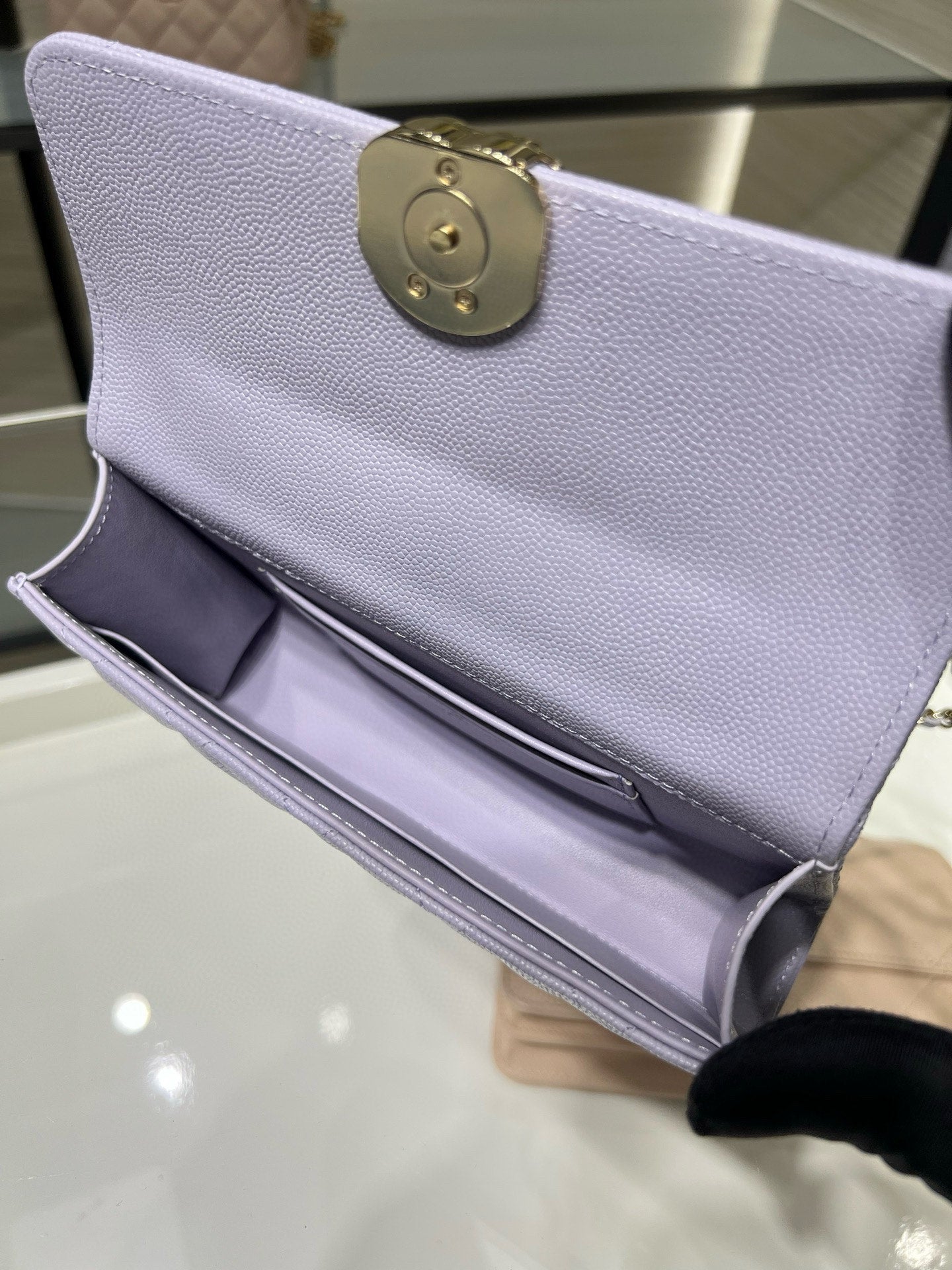 Lavender leather mini bag with round gold emblem at top and chain detail