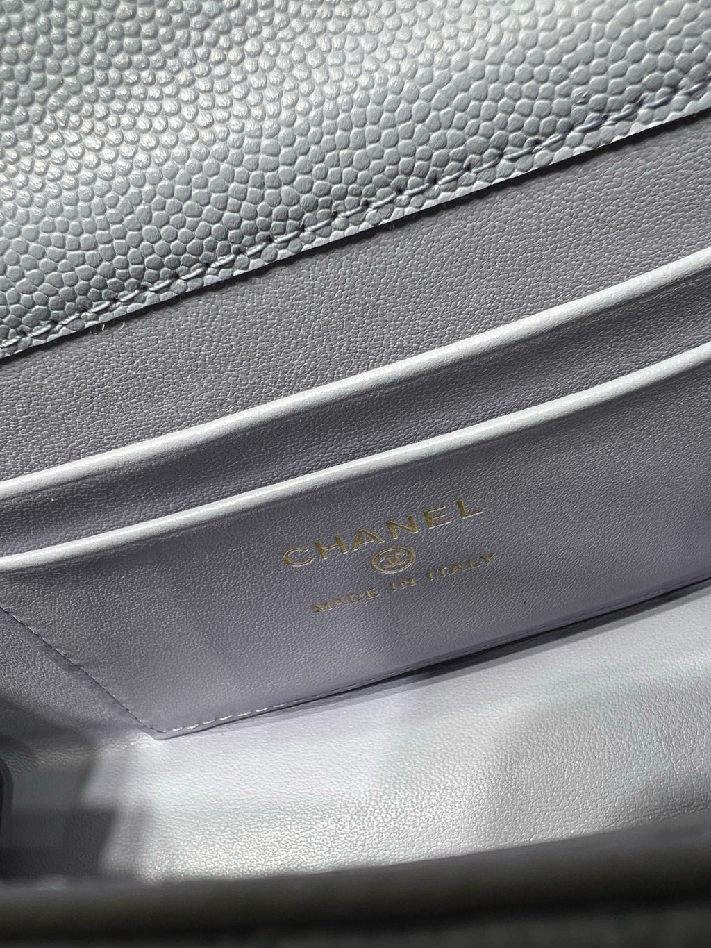 Lavender leather handbag with textured grain and gold logo stamping on interior flap