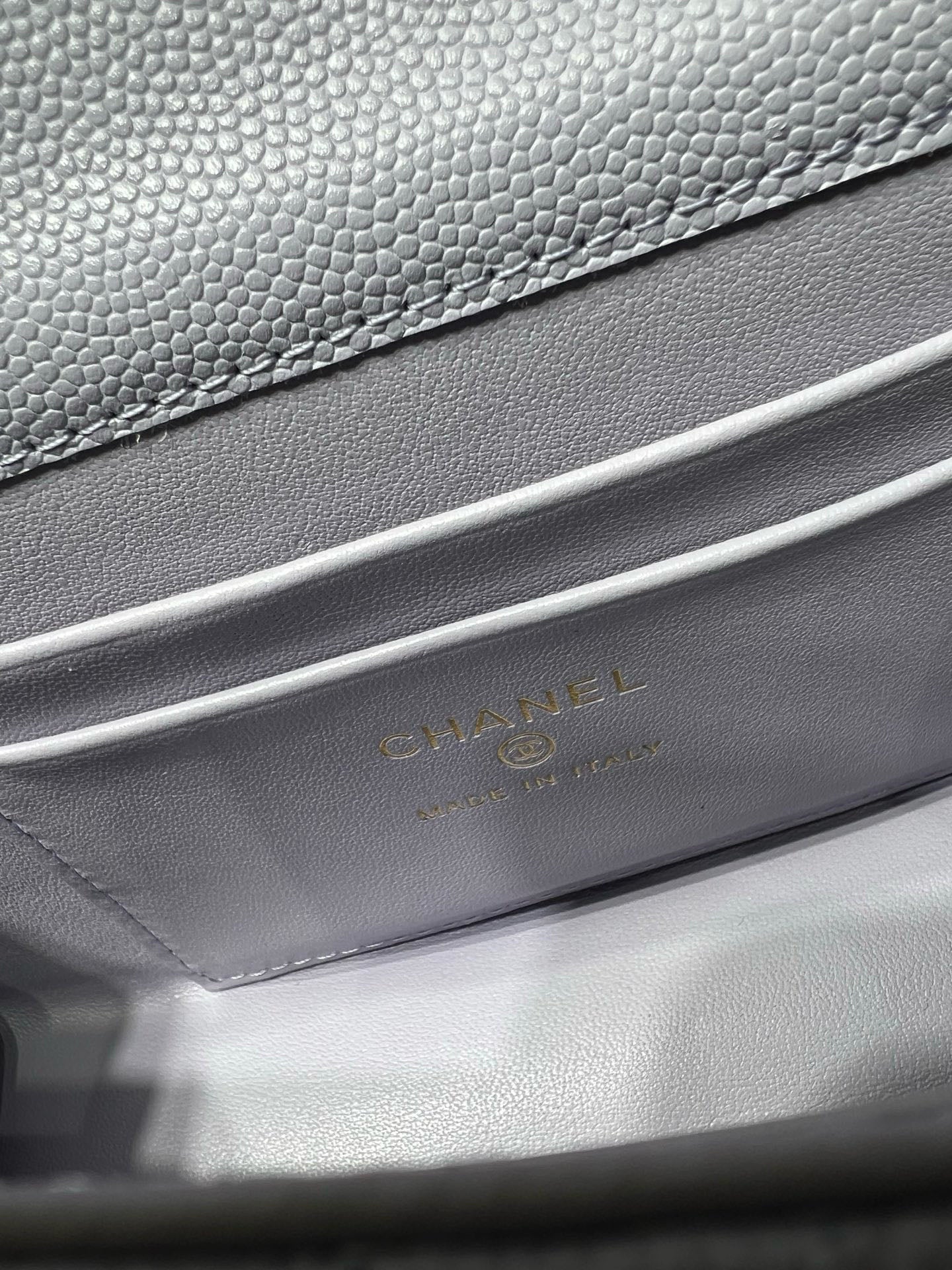 Lavender leather handbag with textured grain and gold logo stamping on interior flap