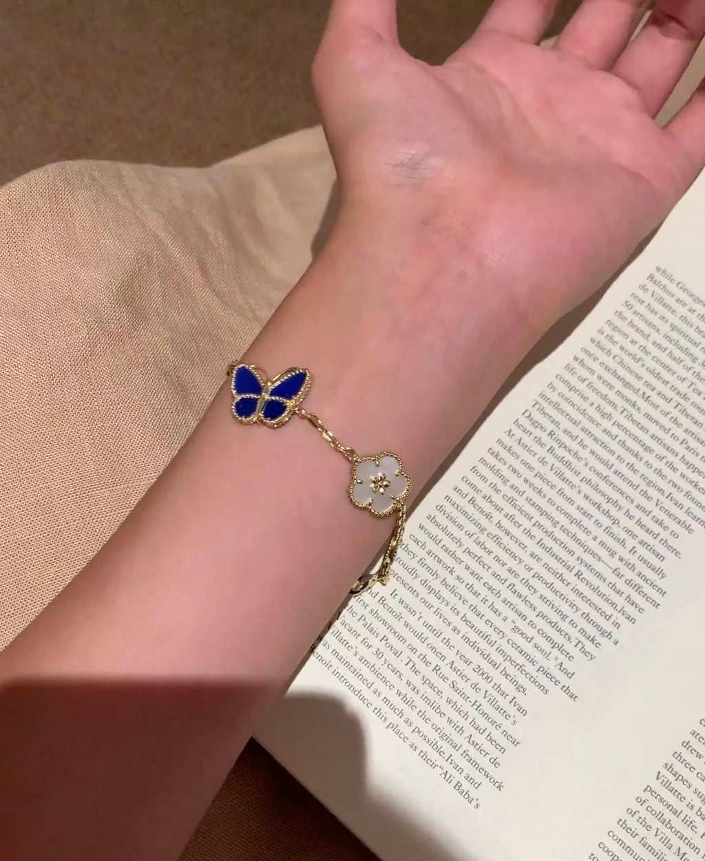 Gold-tone bracelet with blue butterfly centerpiece and white clover charm details