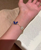 Gold-tone bracelet with blue butterfly centerpiece and white clover charm details