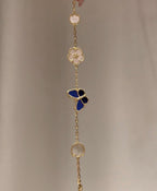 Gold-tone drop bracelet with blue butterfly, white clover, and round medallion charm