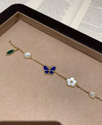 Gold-tone bracelet with blue butterfly, white clover, and green leaf charms